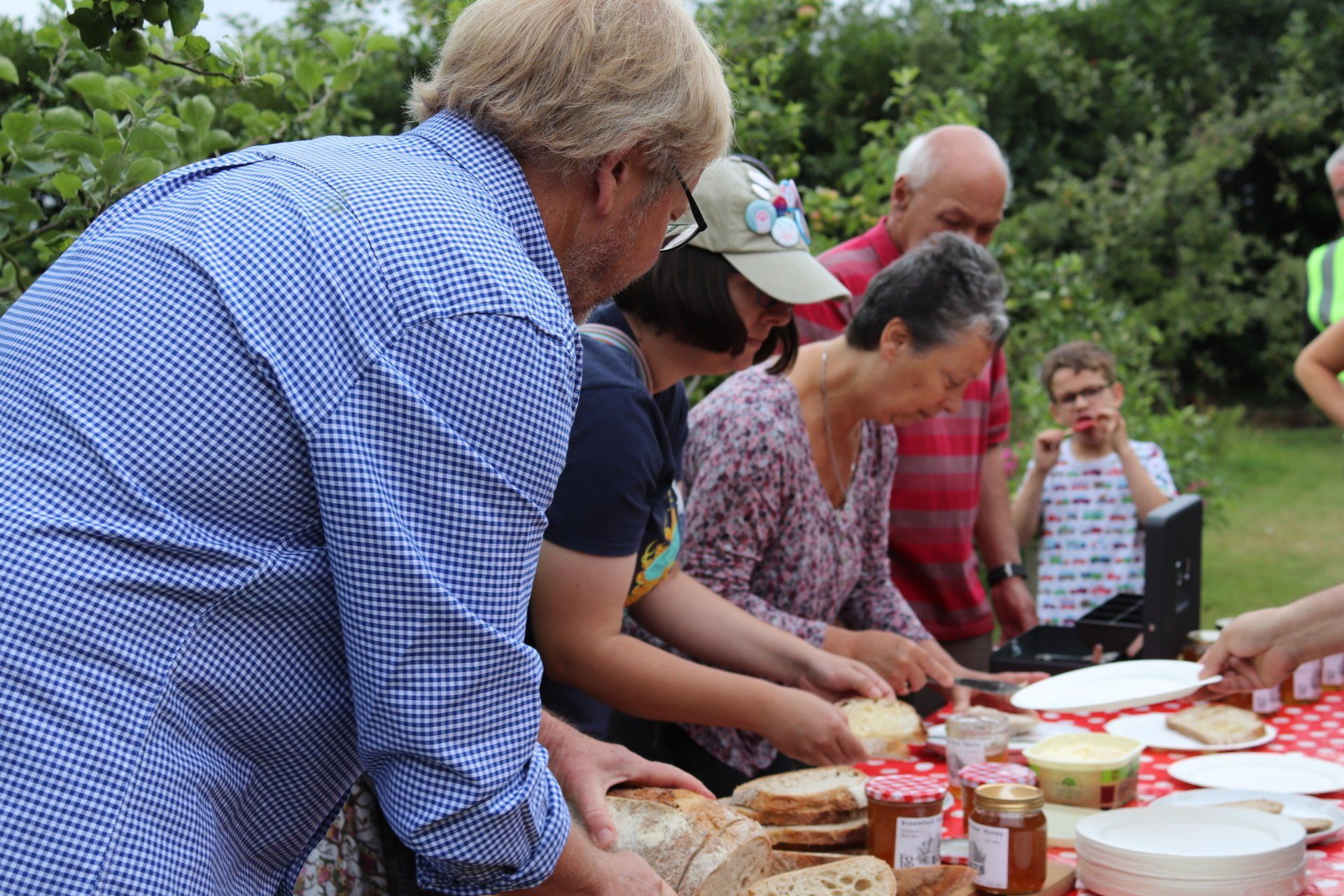 A group of people are standing around a table cutting bread.