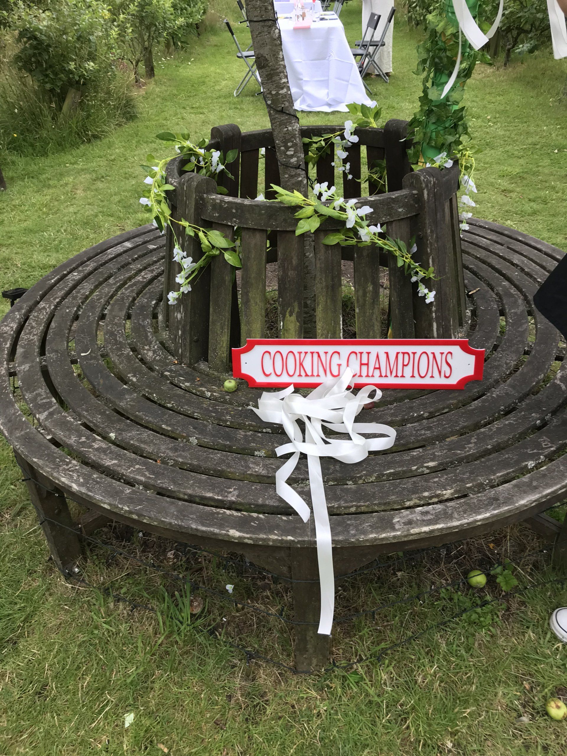 A wooden bench with a sign on it that says cooking champions.