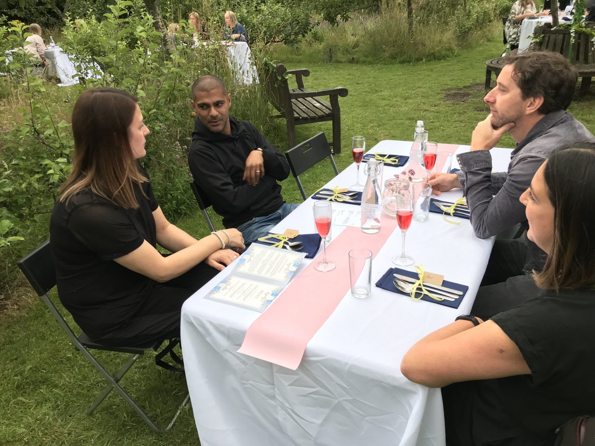 A group of people are sitting around a table in the grass.
