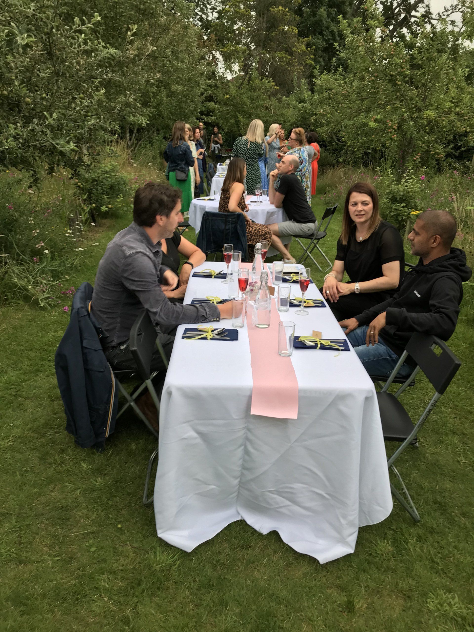 A group of people are sitting at a table in the grass.