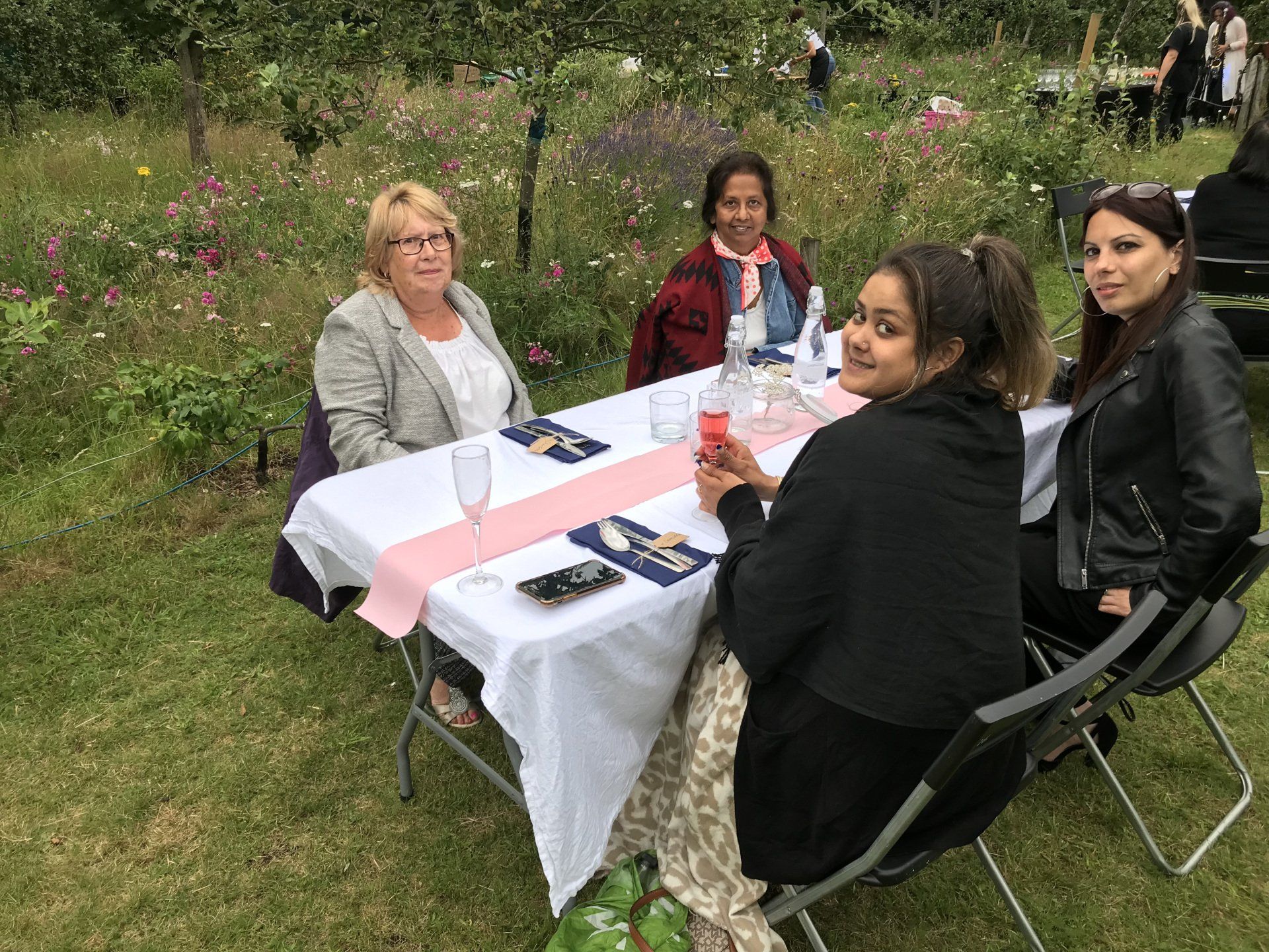 A group of women are sitting at a table in the grass.