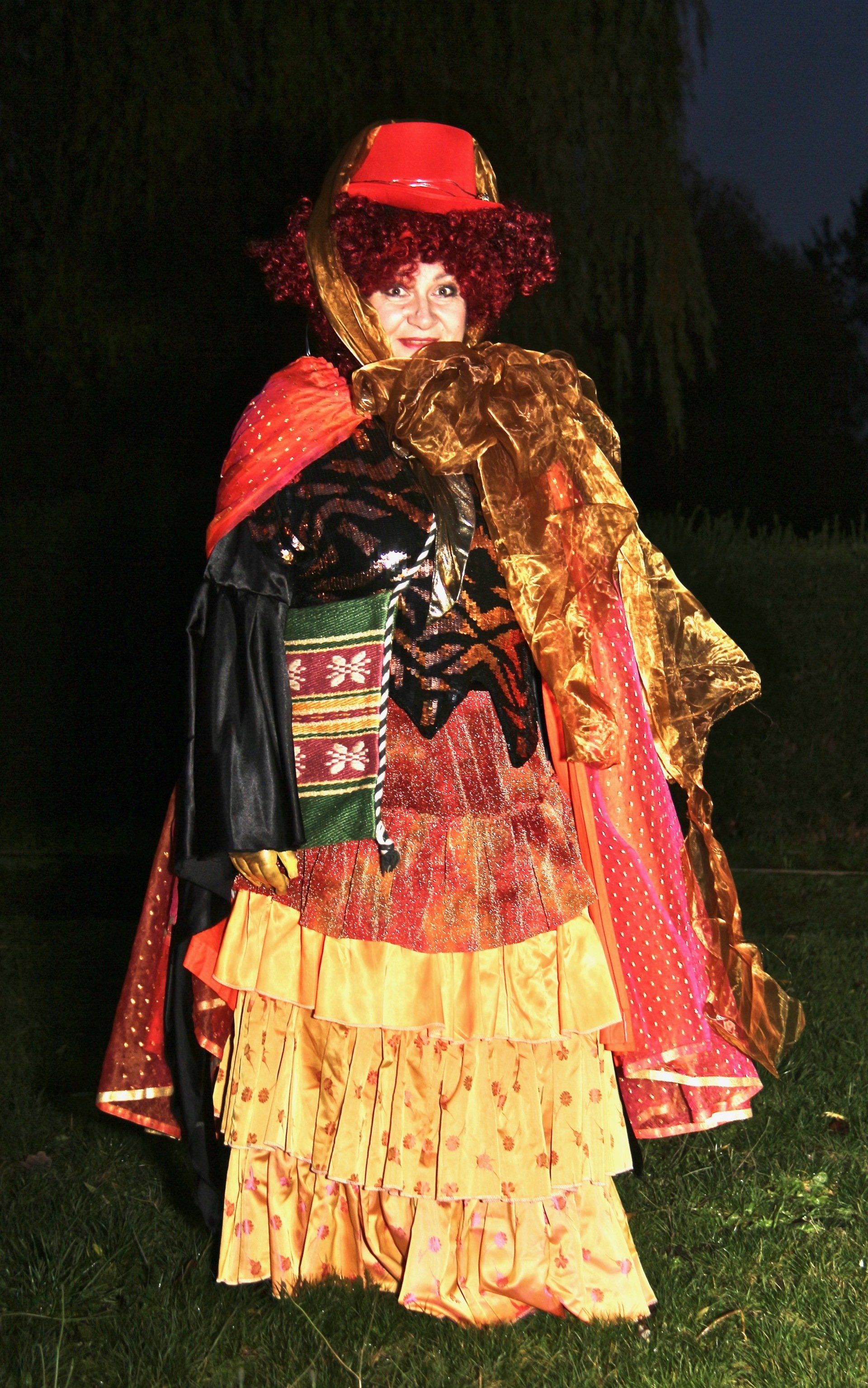 A woman in a clown costume is standing in the grass