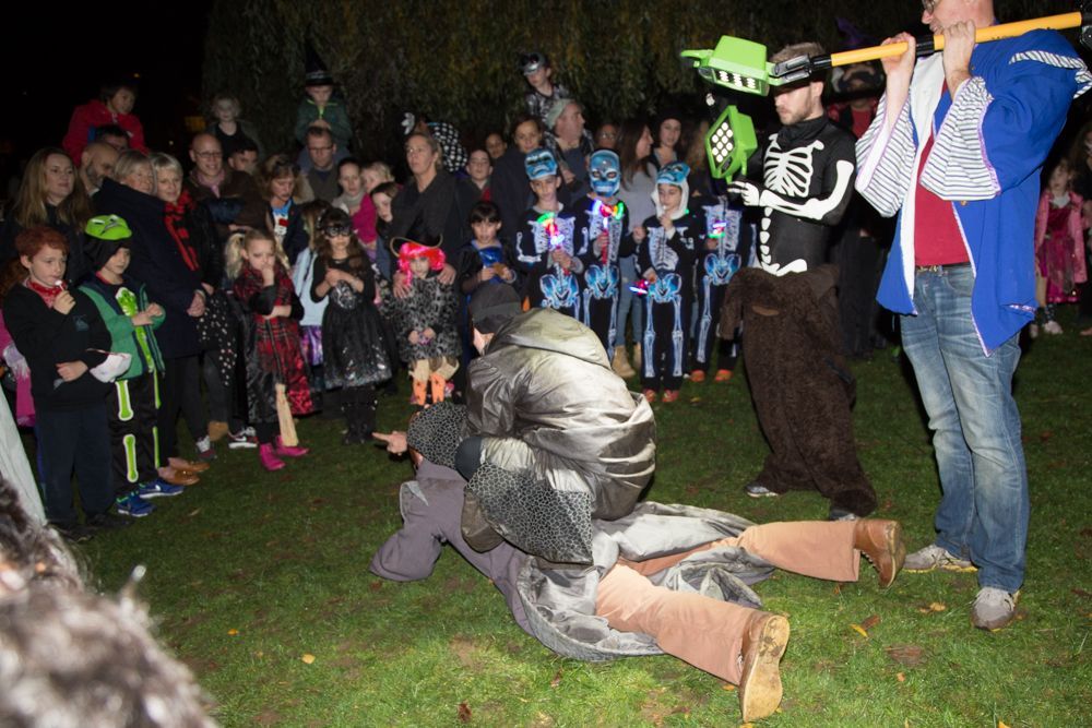 A group of people dressed in halloween costumes are playing a game on the grass.