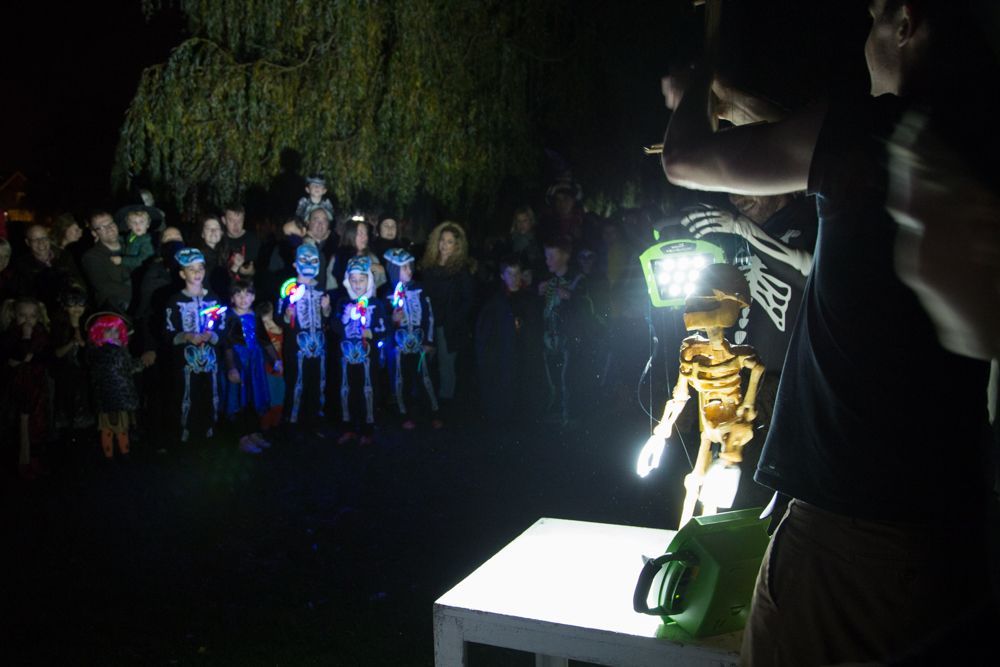 A group of people are standing around a table with a skeleton on it.