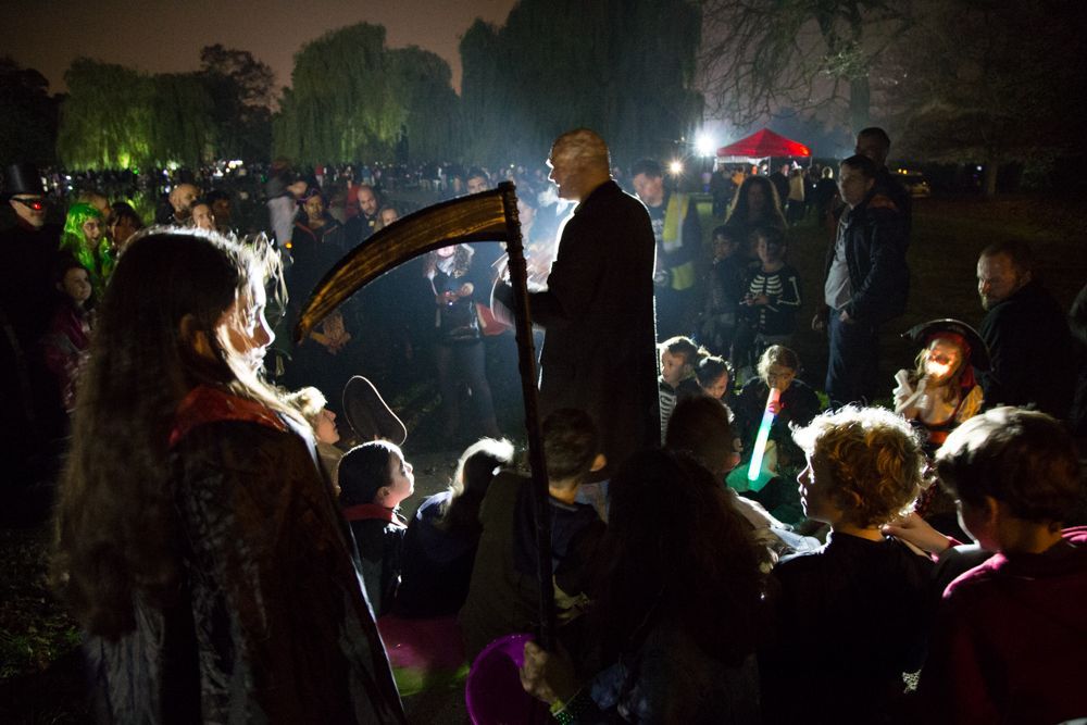 A man is holding a scythe in front of a crowd of people.