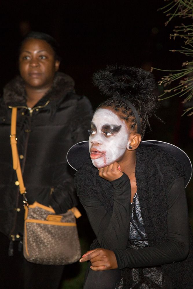 A woman with white paint on her face is standing next to another woman.