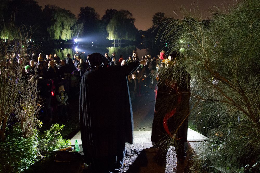 A group of people are standing in front of a lake at night.