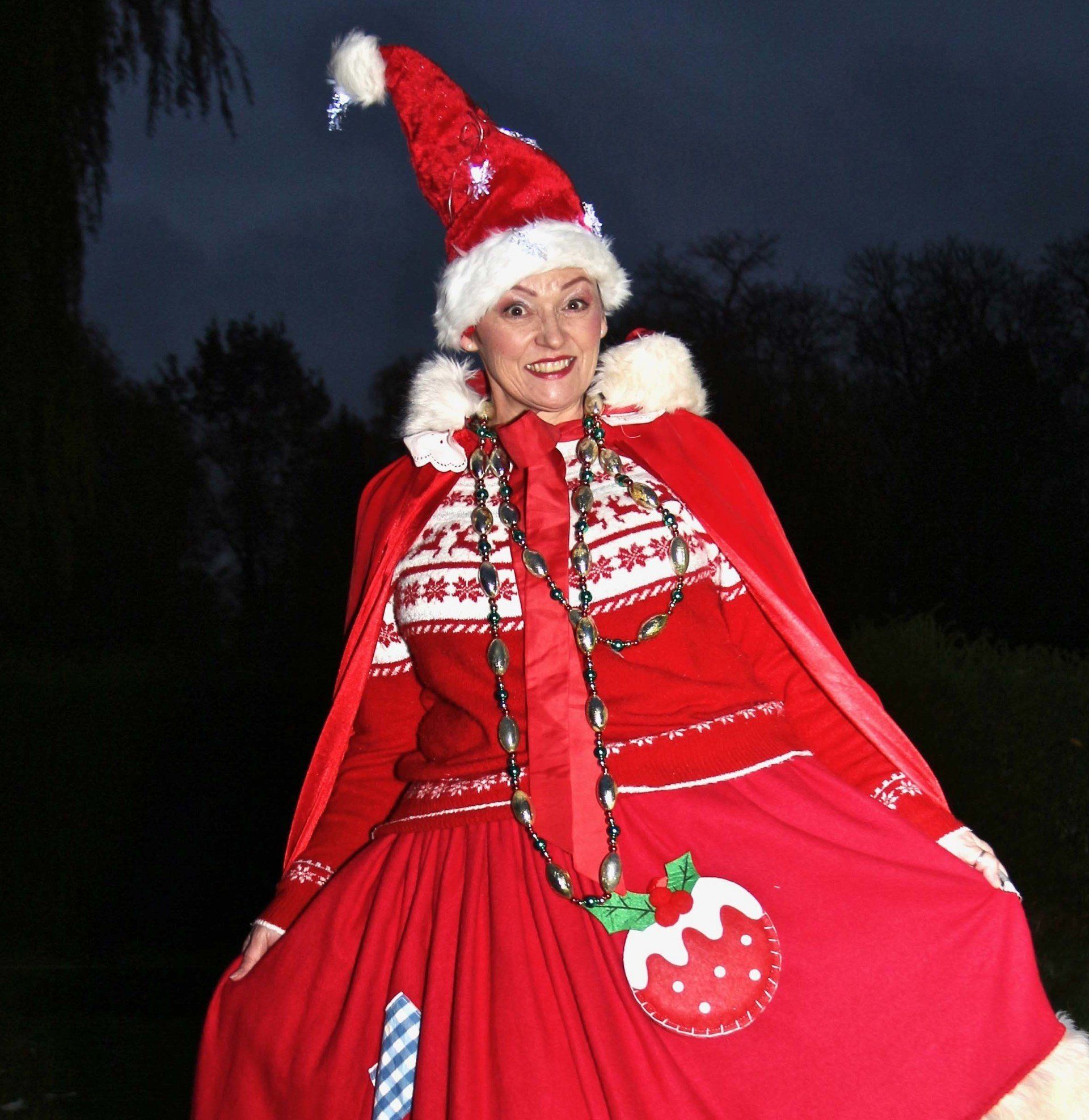 A woman wearing a santa hat and a red cape