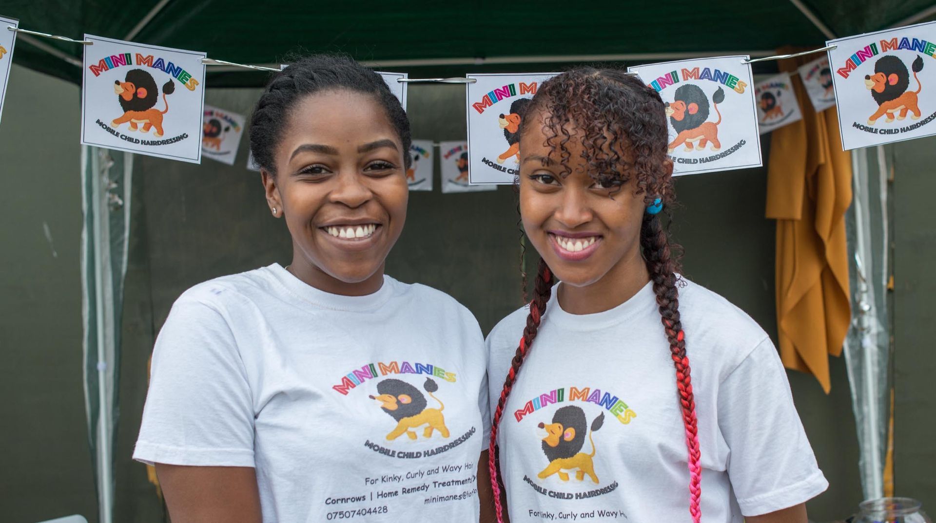 Two girls wearing white shirts with lions on them are standing next to each other.