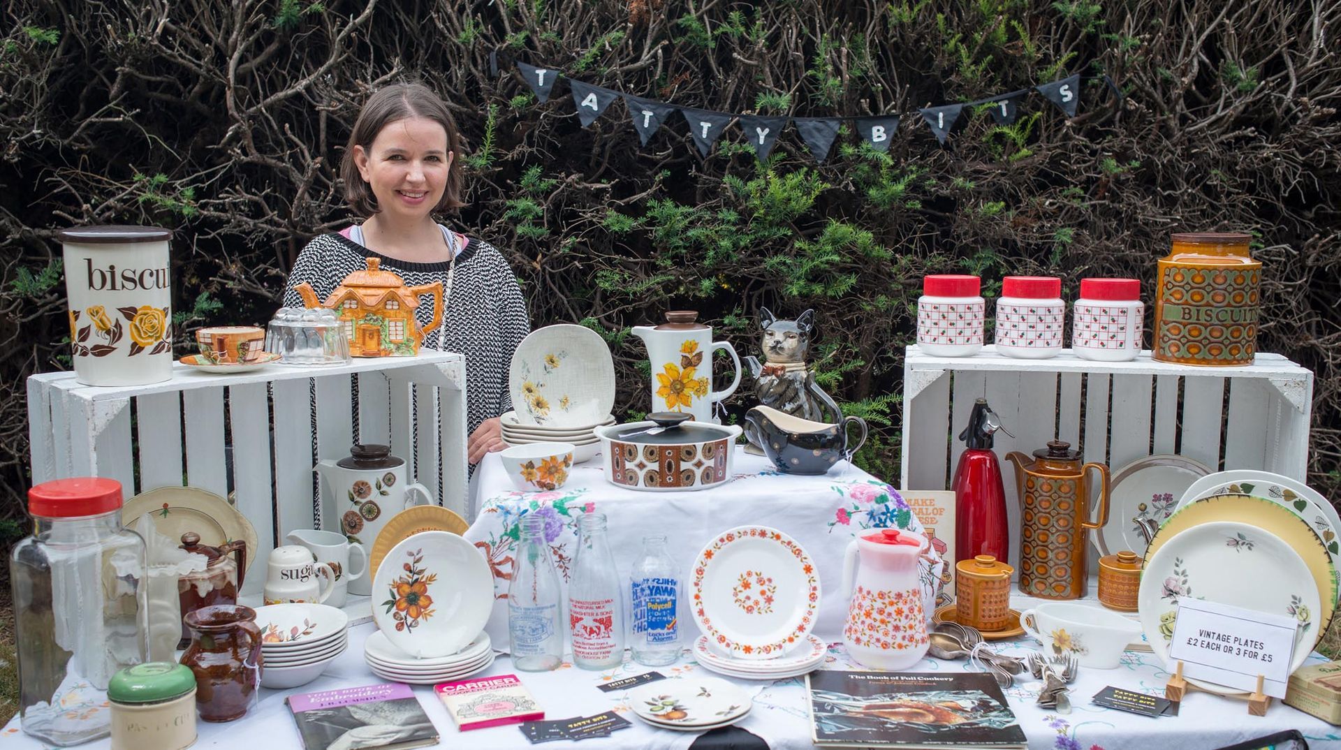 A woman is standing in front of a table filled with lots of dishes.