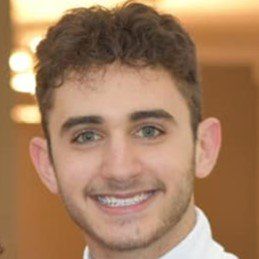 A young man with a beard is smiling for the camera.