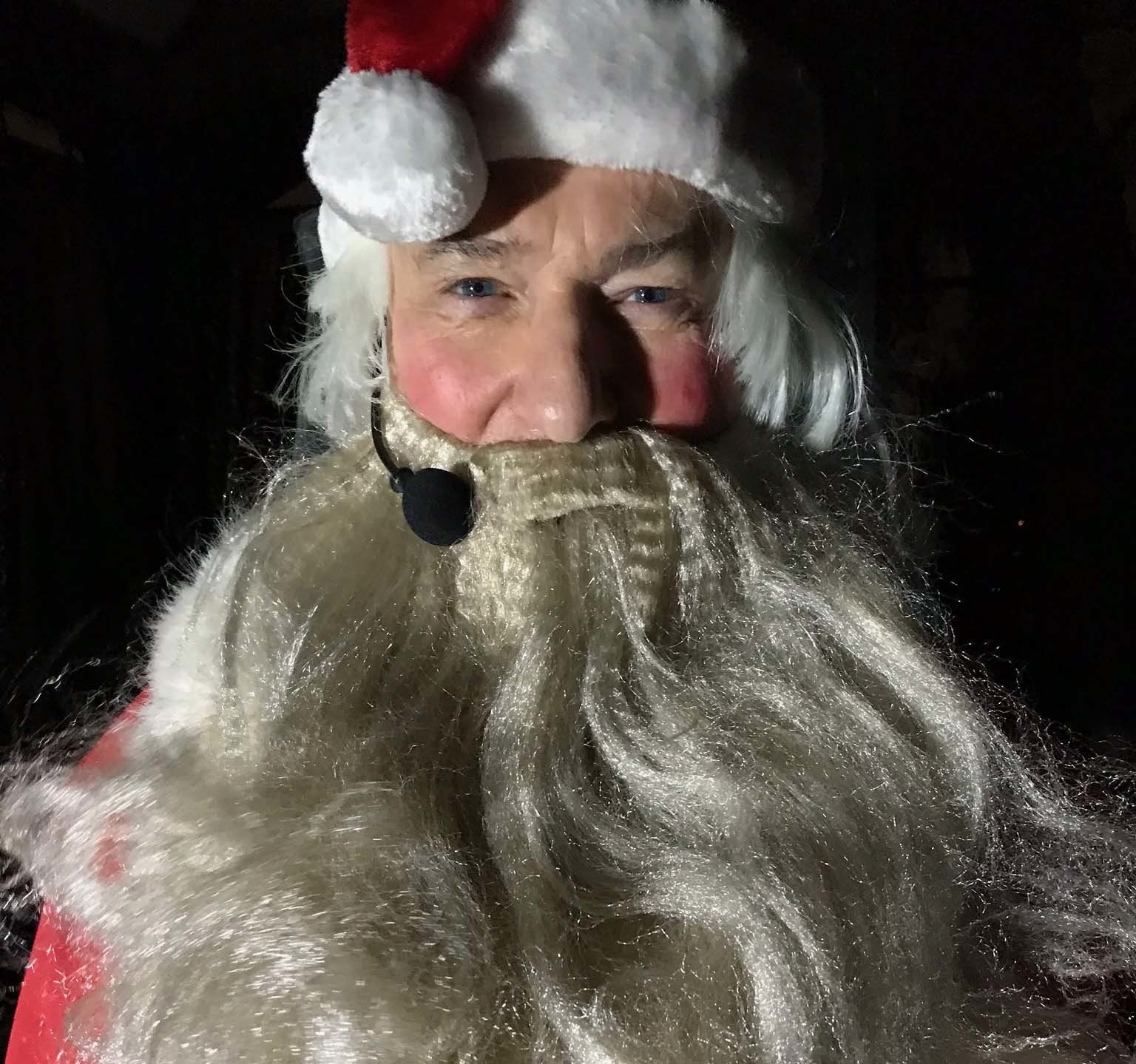 A man with a santa hat and beard is wearing a scarf around his neck