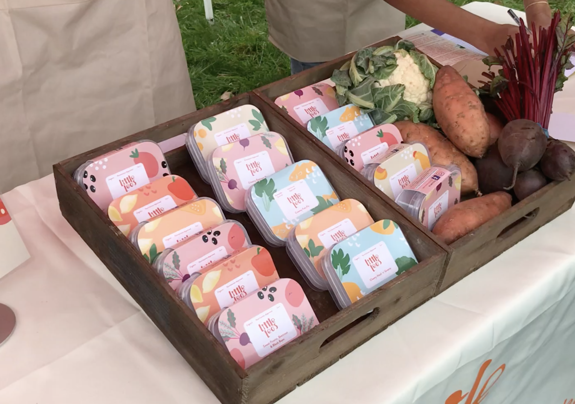 A wooden tray filled with fruits and vegetables on a table.