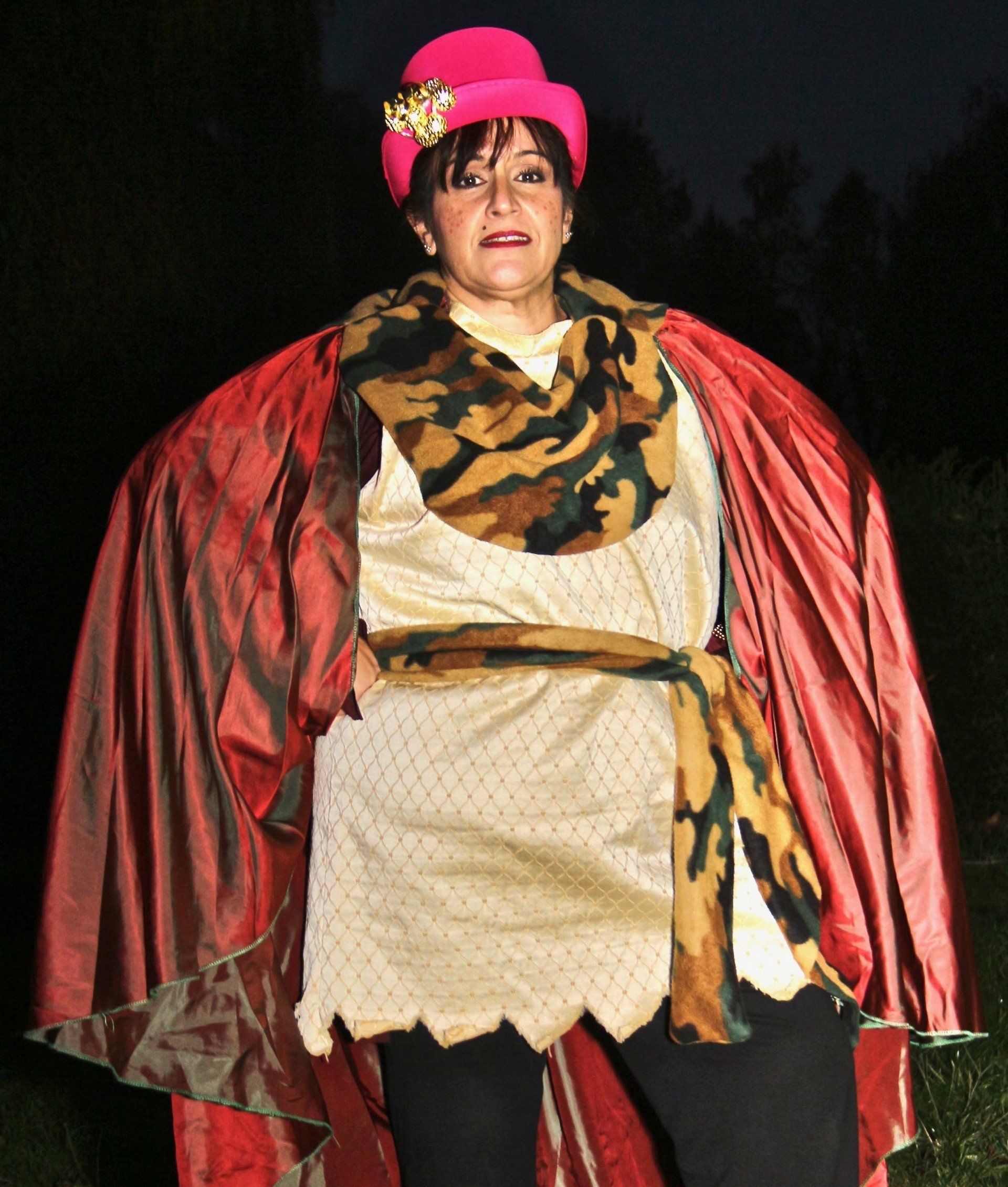 A woman wearing a pink top hat and a red cape