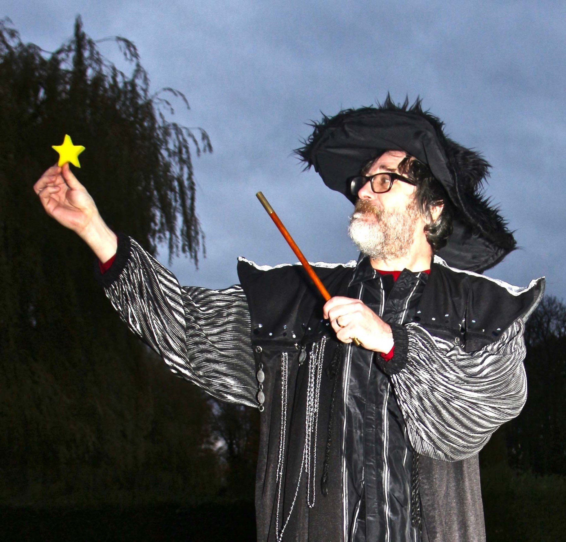 A man in a wizard costume is holding a wand and a star