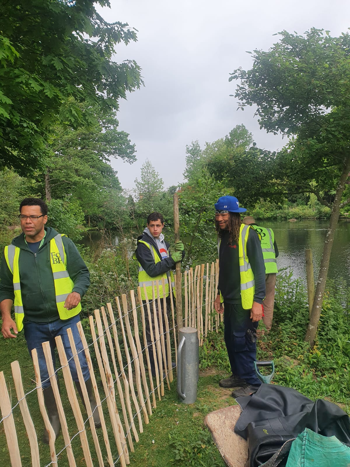 A group of men are standing next to a wooden fence.