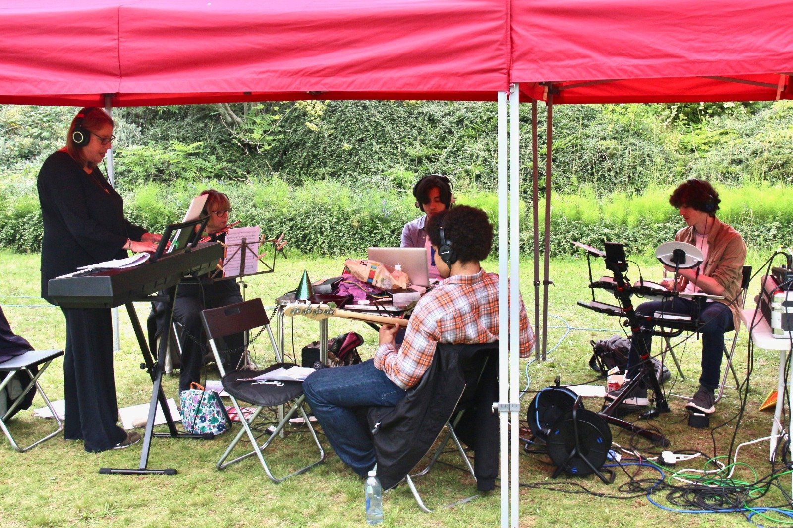 A group of people are playing instruments under a red tent.