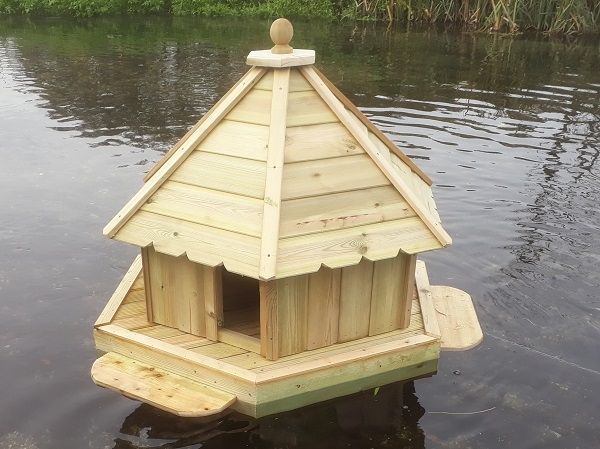 A wooden birdhouse is floating on top of a body of water.