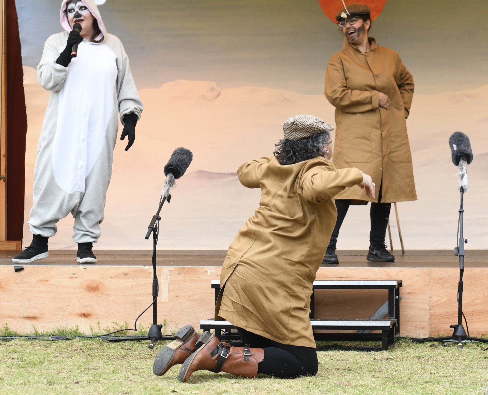 A woman in a brown coat is kneeling down in front of a microphone.