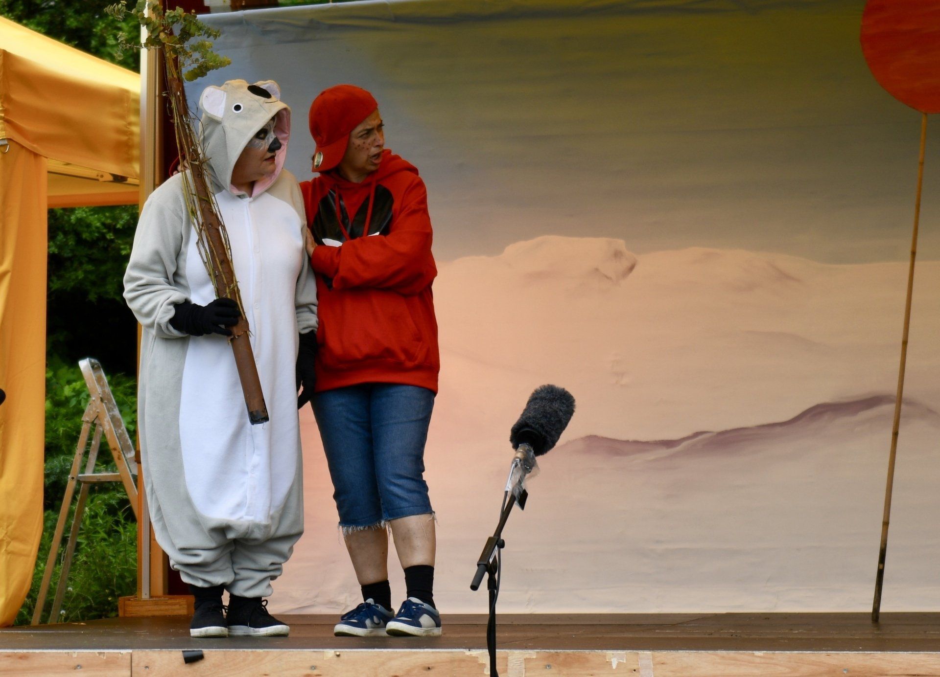 A man in a red hoodie stands next to a woman in a koala costume
