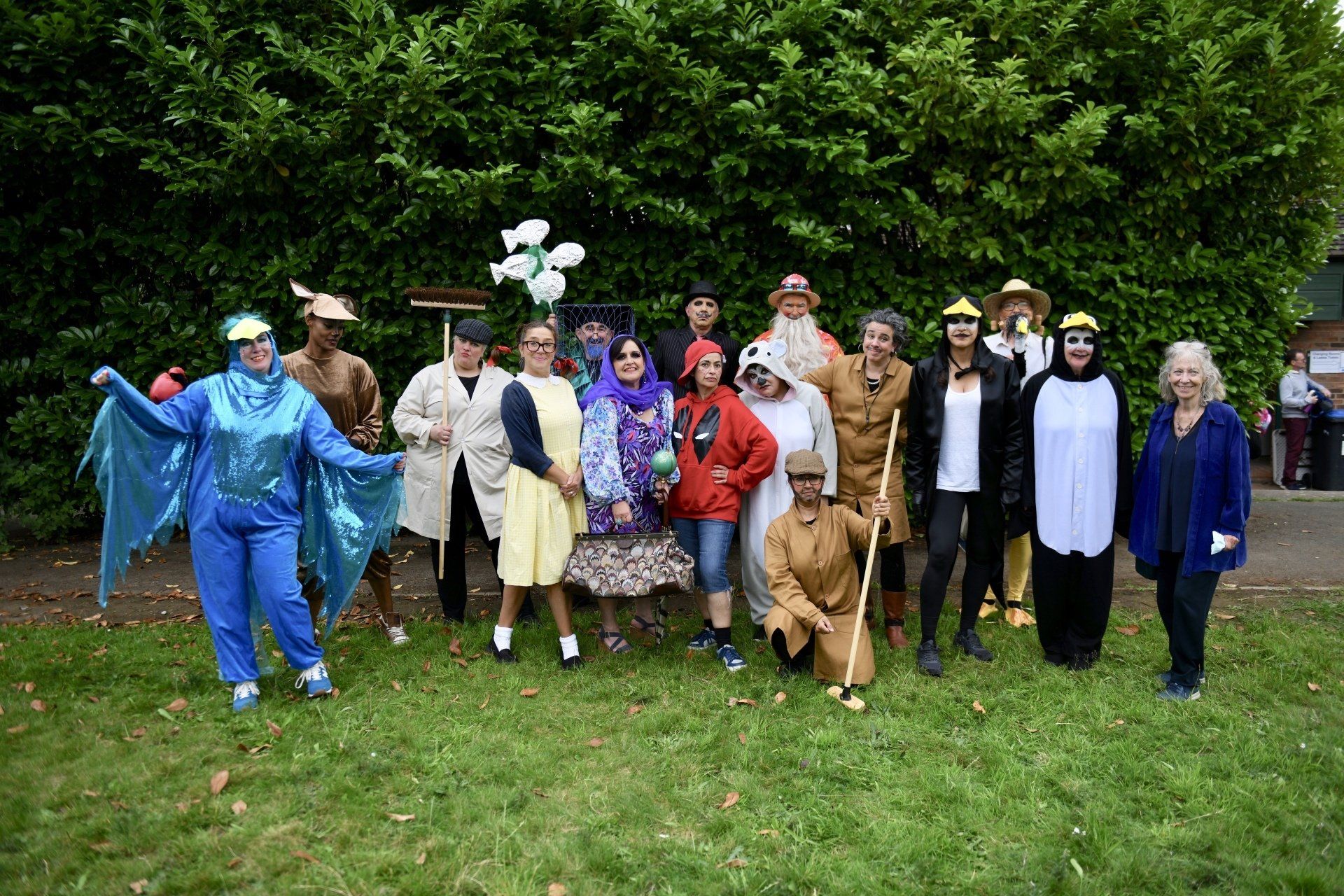 A group of people dressed in costumes are posing for a picture in a park.