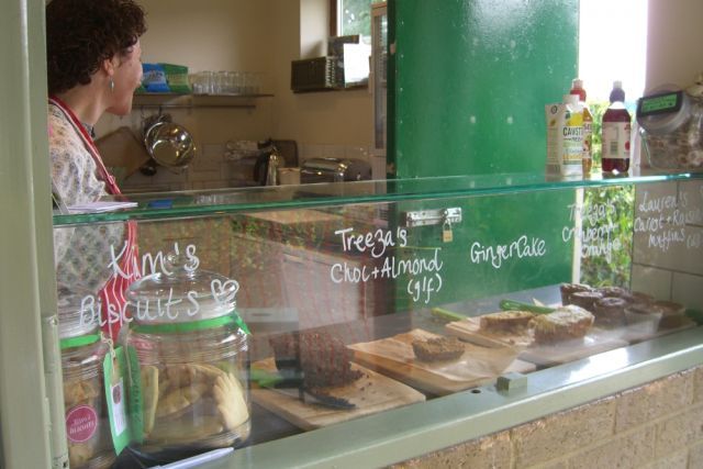 A woman is standing behind a counter selling food.
