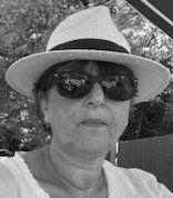 A black and white photo of a woman wearing a hat and sunglasses.