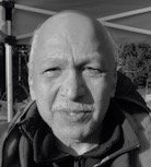 A black and white photo of a bald man with a beard.