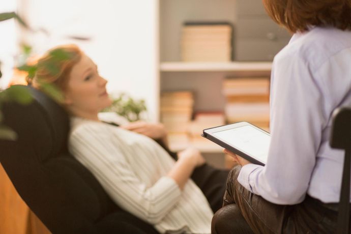 A woman is sitting in a chair talking to a doctor.