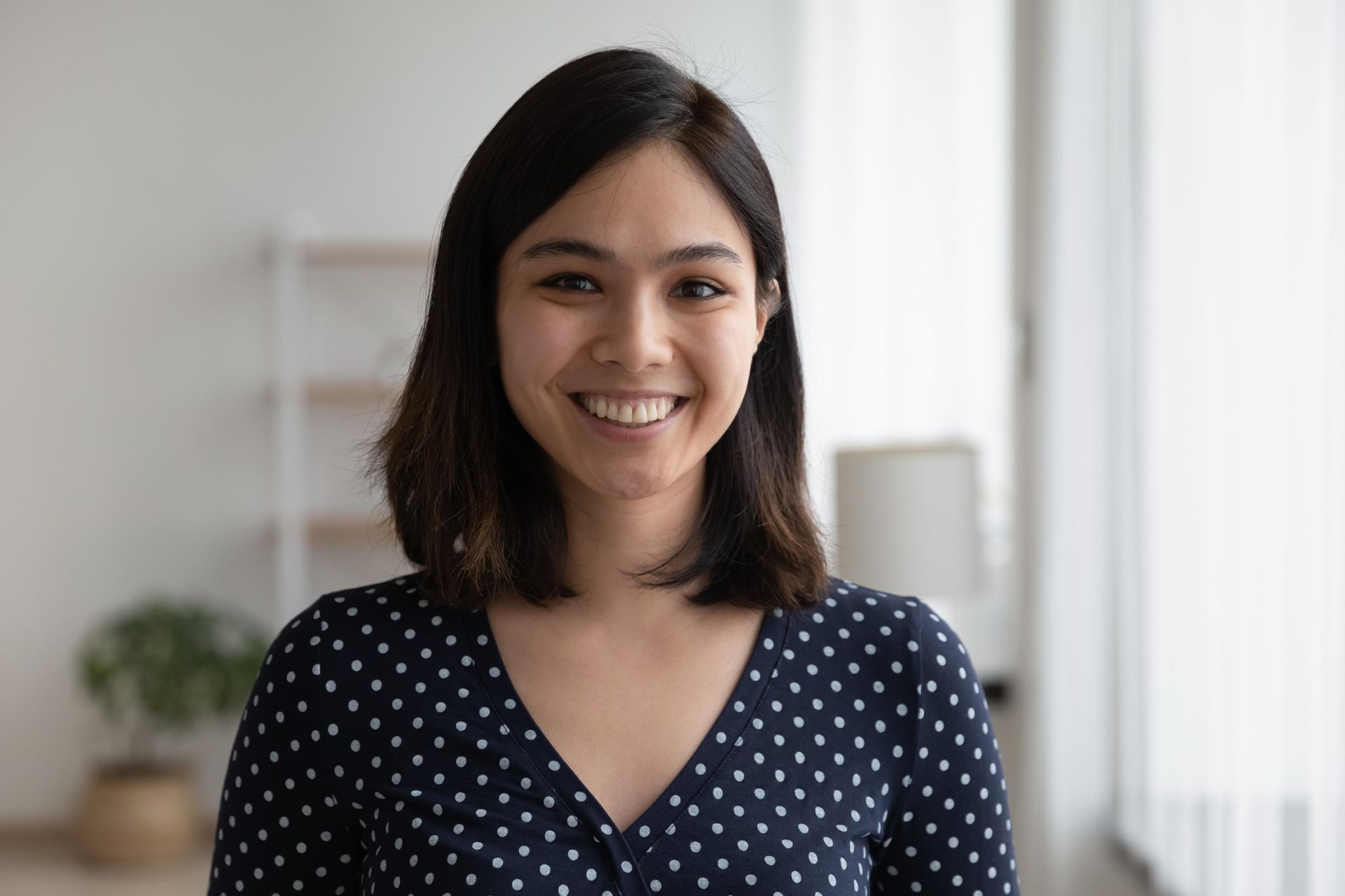 A woman in a blue polka dot shirt is smiling for the camera.