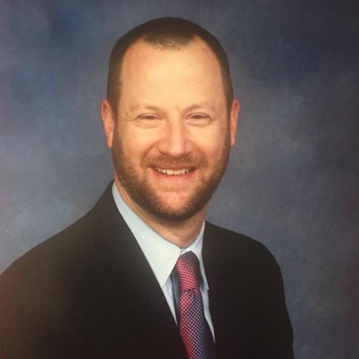 A man in a suit and tie smiles for the camera