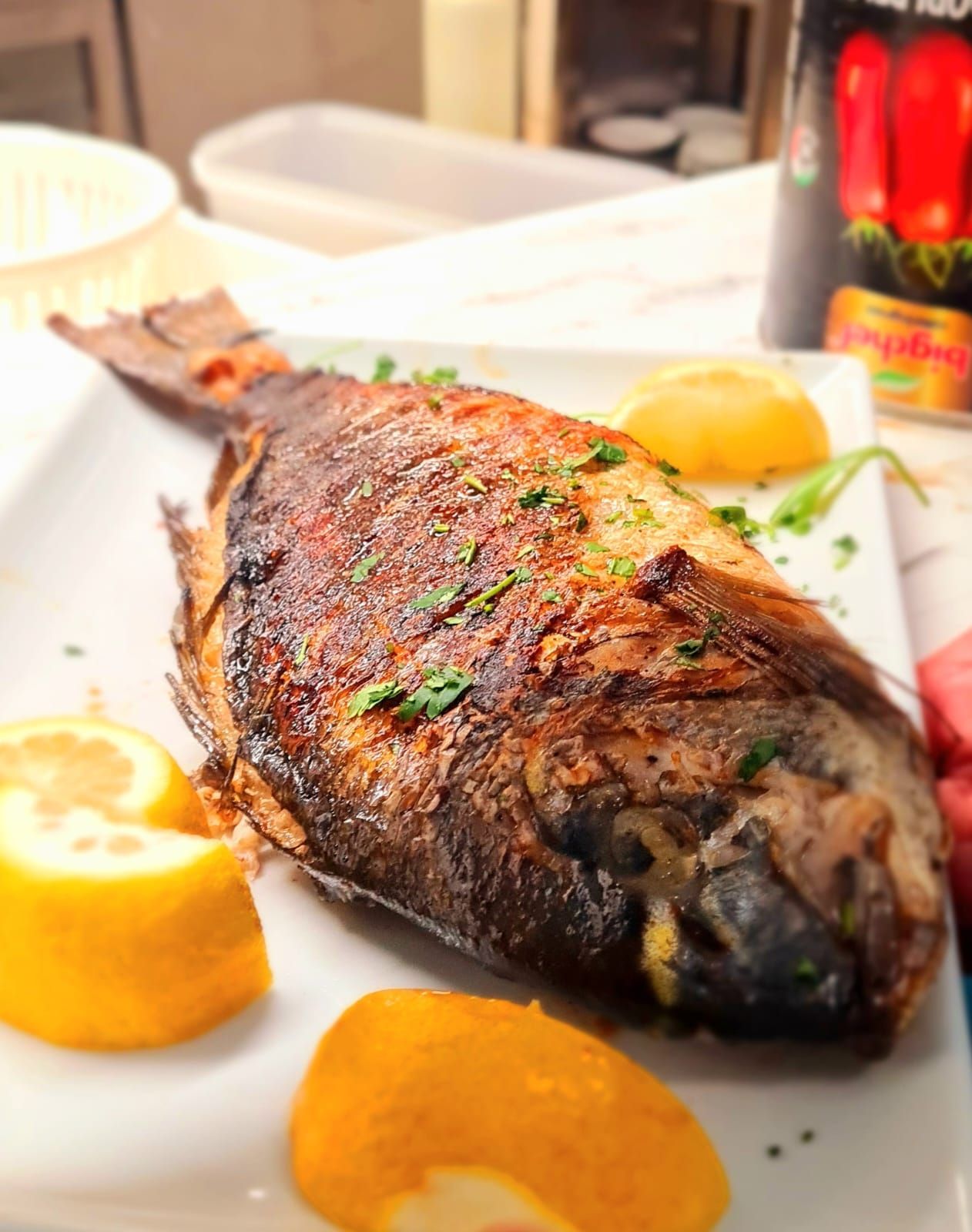 Un pesce alla griglia su un piatto bianco con fette di limone