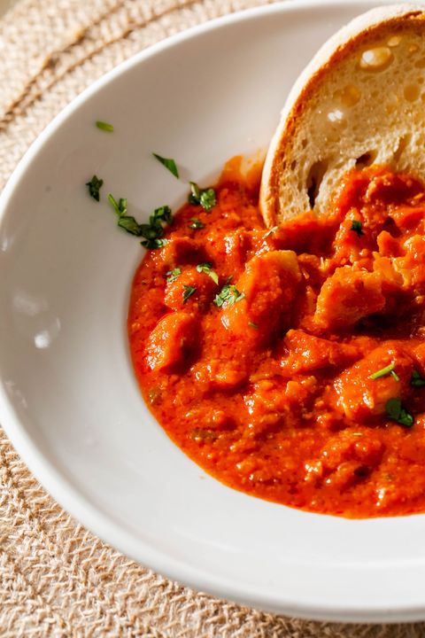 Una ciotola di salsa di pomodoro con un pezzo di pane dentro.