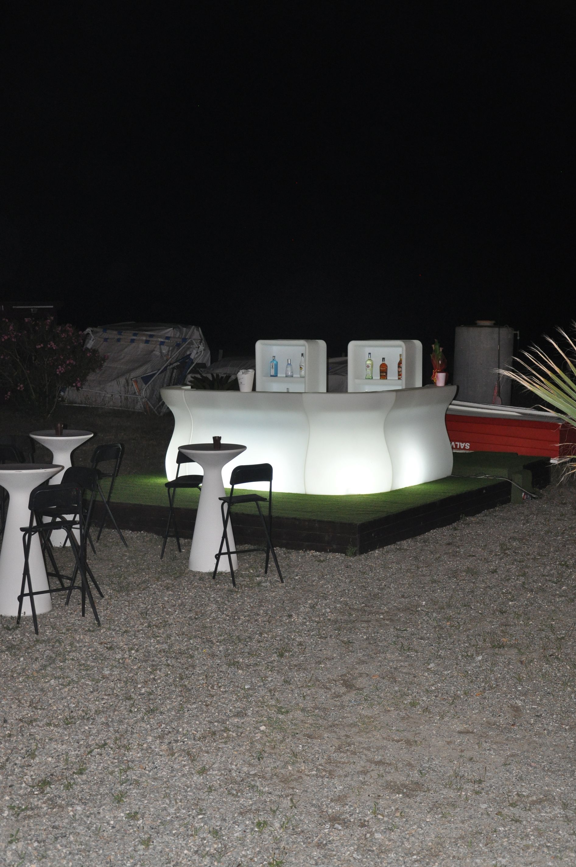 Un bar con tavoli e sgabelli è illuminato di notte.