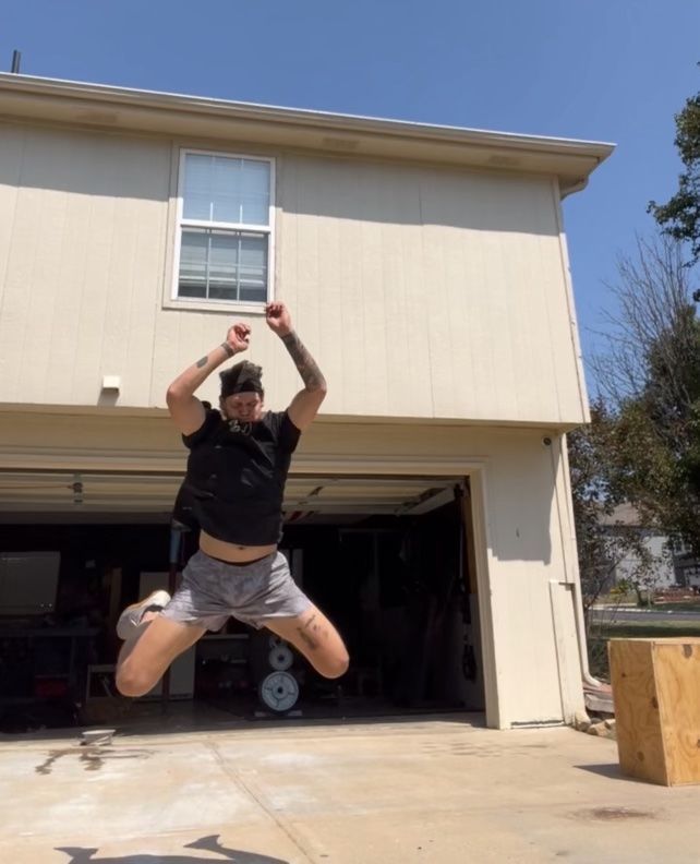 A man is jumping in the air in front of a house.