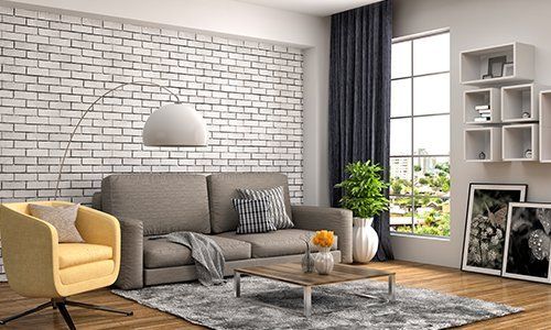 Soggiorno con parete di pietra,sofá grigio, poltrona gialla e lampadina di disegno