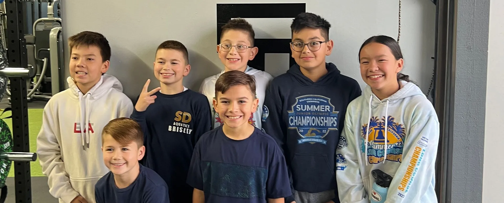 Group of children in a gym posing in front of a 