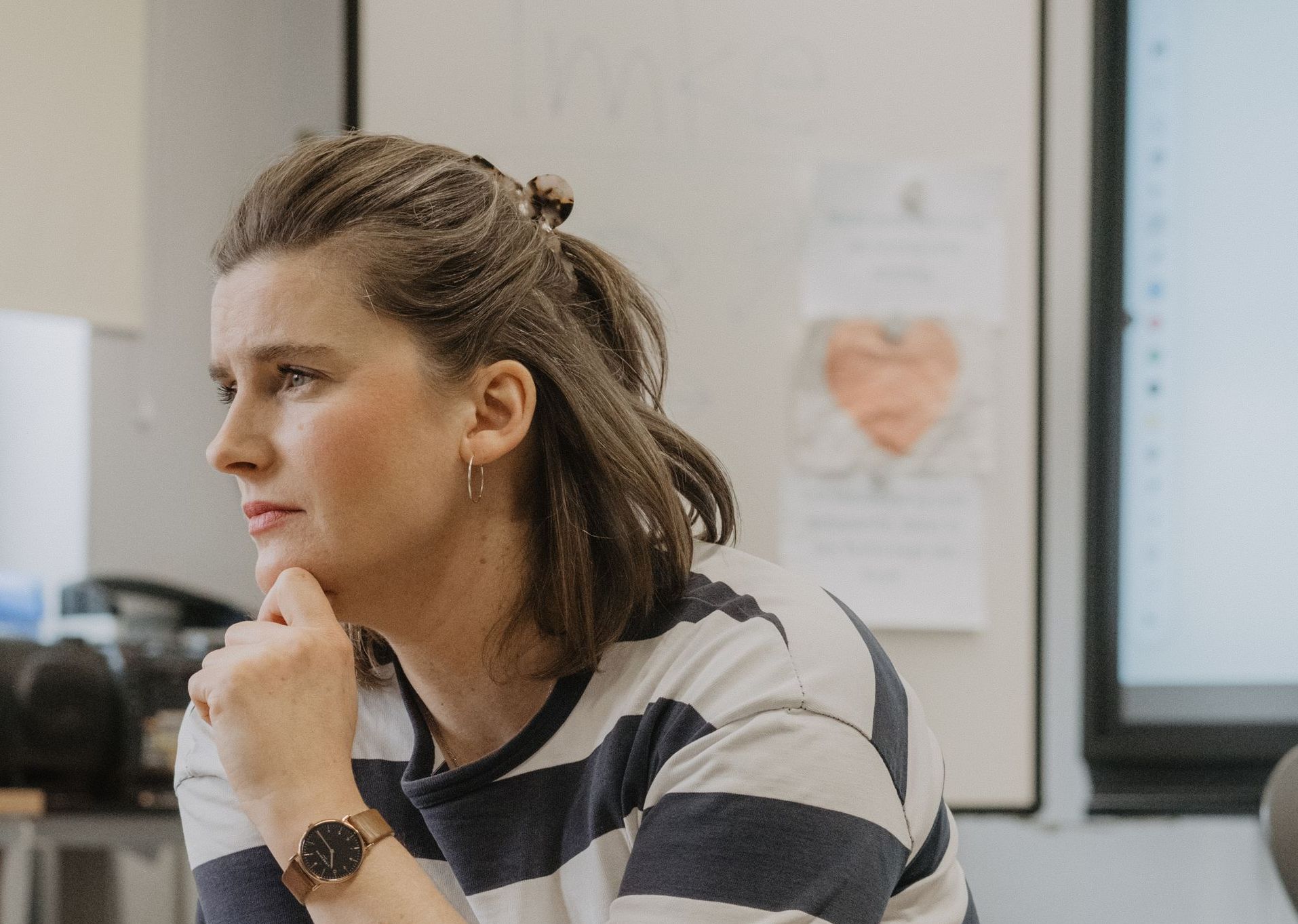 Nachdenkliche Frau auf Stuhl sitzend im Klassenzimmer, hört gespannt zu.