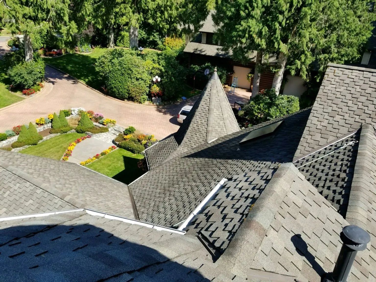 Overhead view of house roof with multiple angles and a landscaped yard with a driveway.
