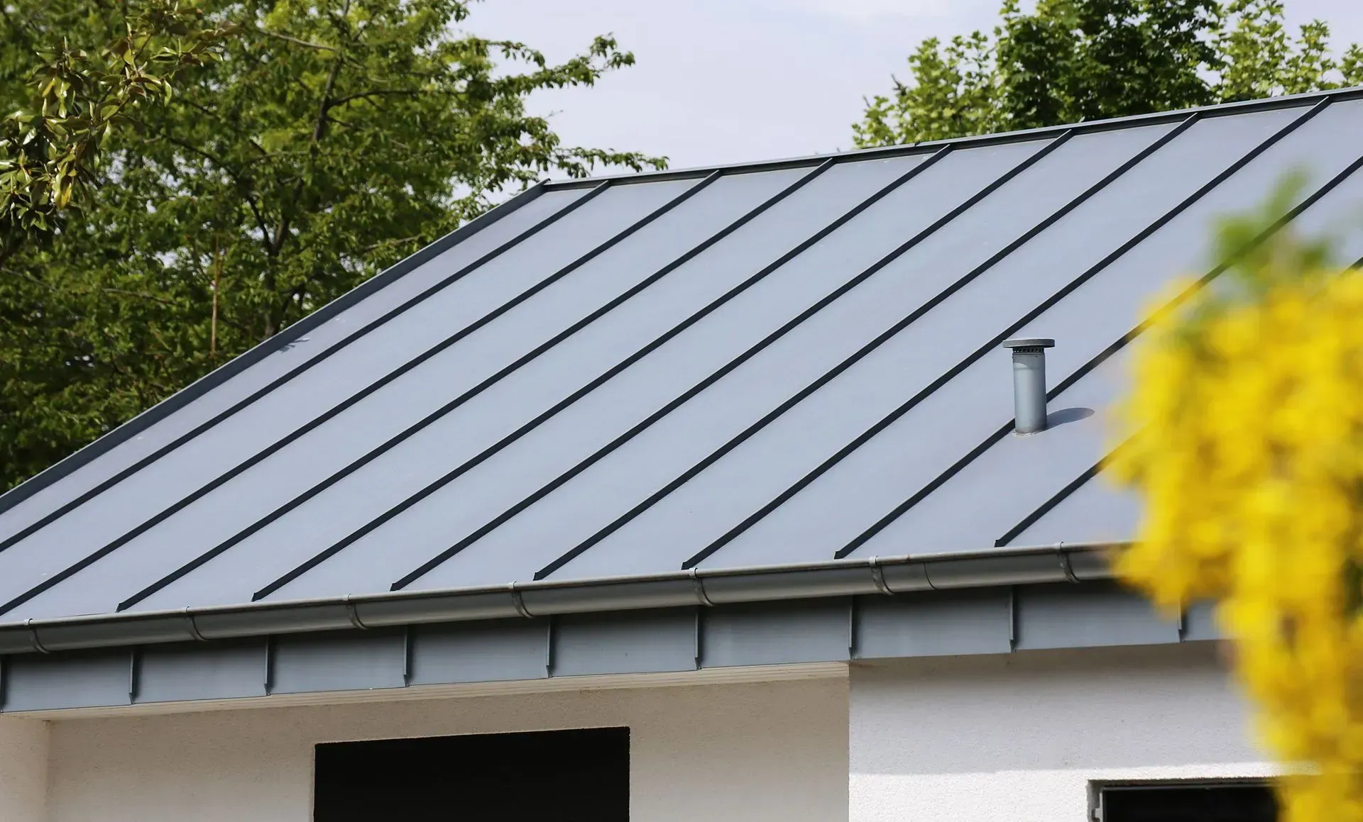 A close up of a roof with a yellow flower in the foreground