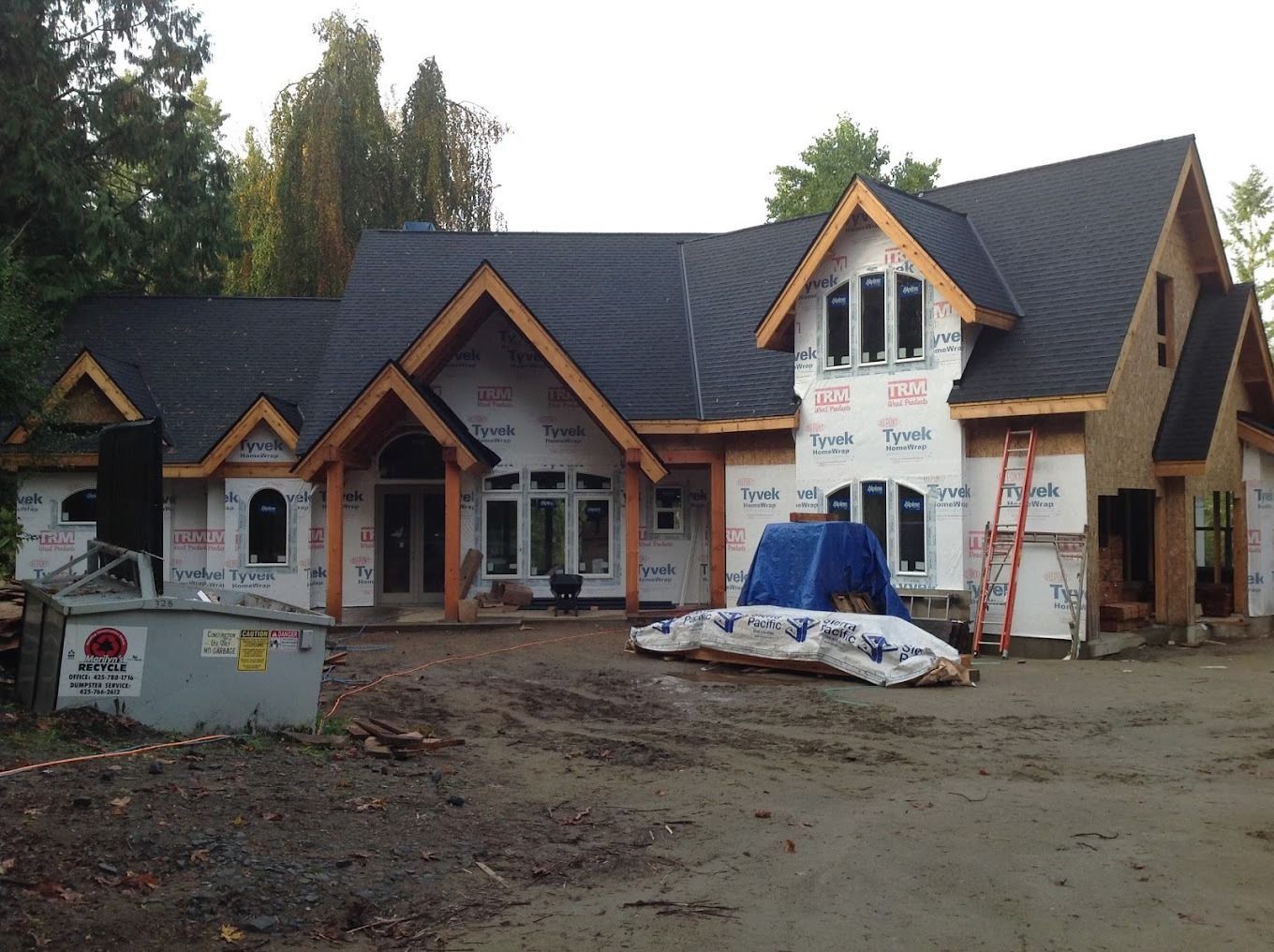 A large house that is being built with a large dumpster in front of it