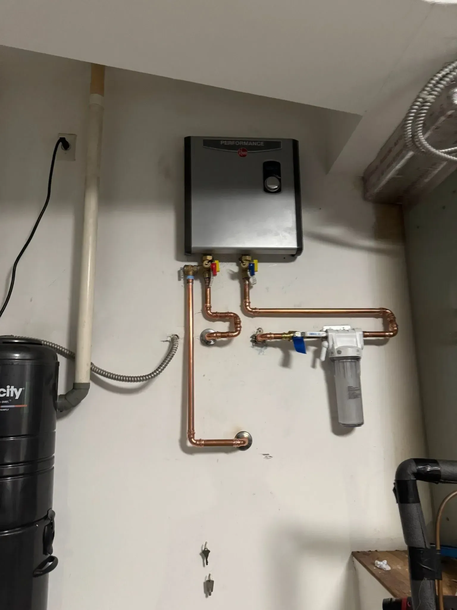 A vacuum cleaner is hanging on a wall next to a water heater.