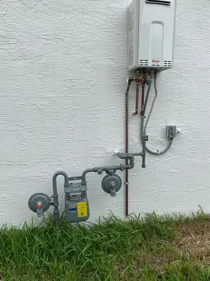 A gas meter is attached to a wall next to a water heater.
