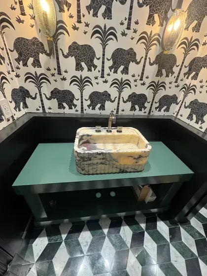 A bathroom with elephants on the wall and a sink