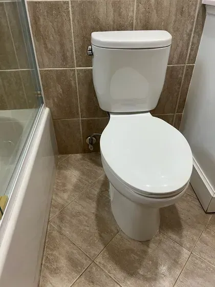 A white toilet is sitting in a bathroom next to a bathtub.