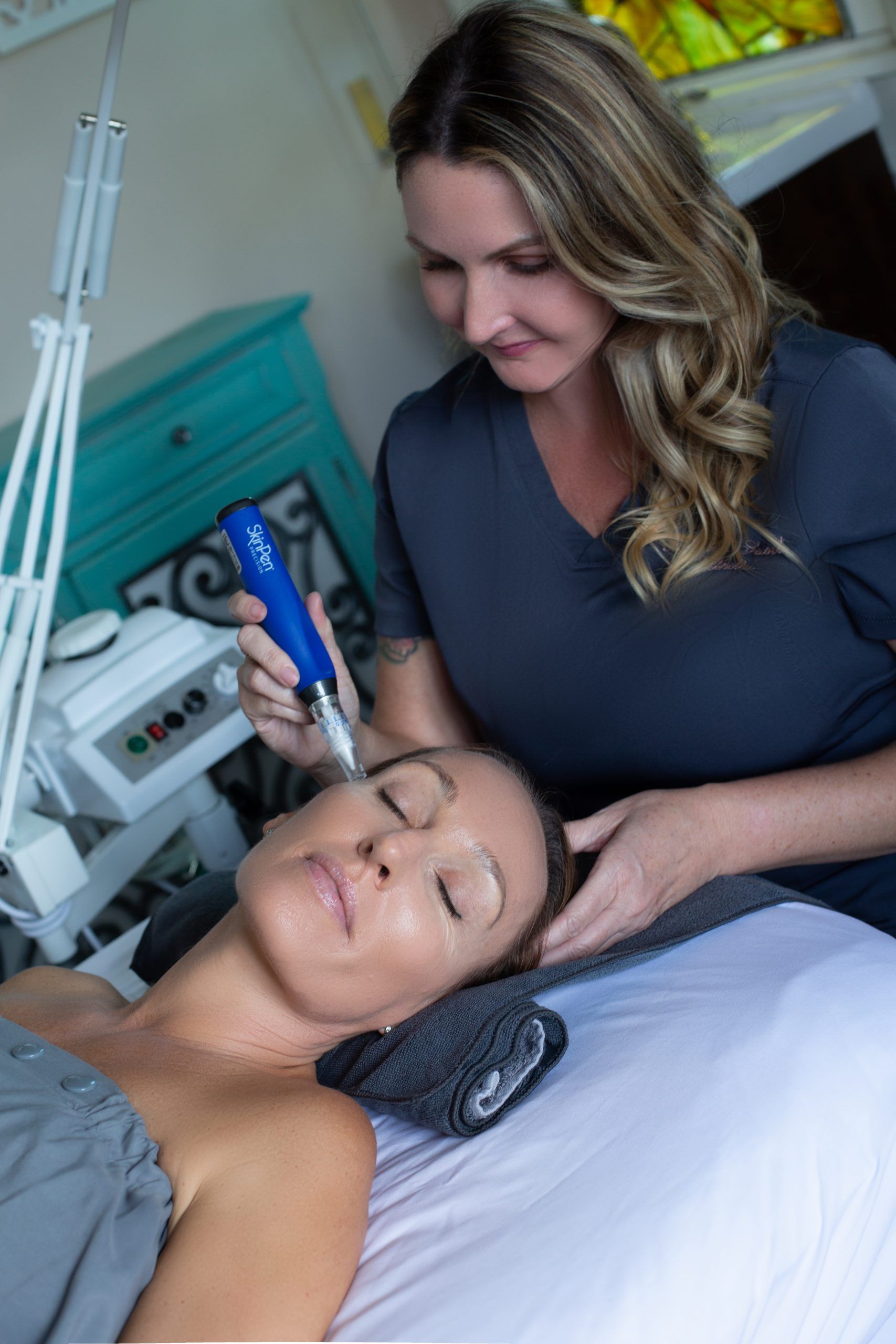 A woman is laying on a bed getting a treatment on her face.