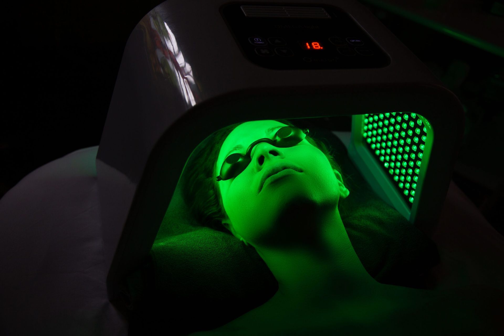A woman is getting a green light treatment on her face.