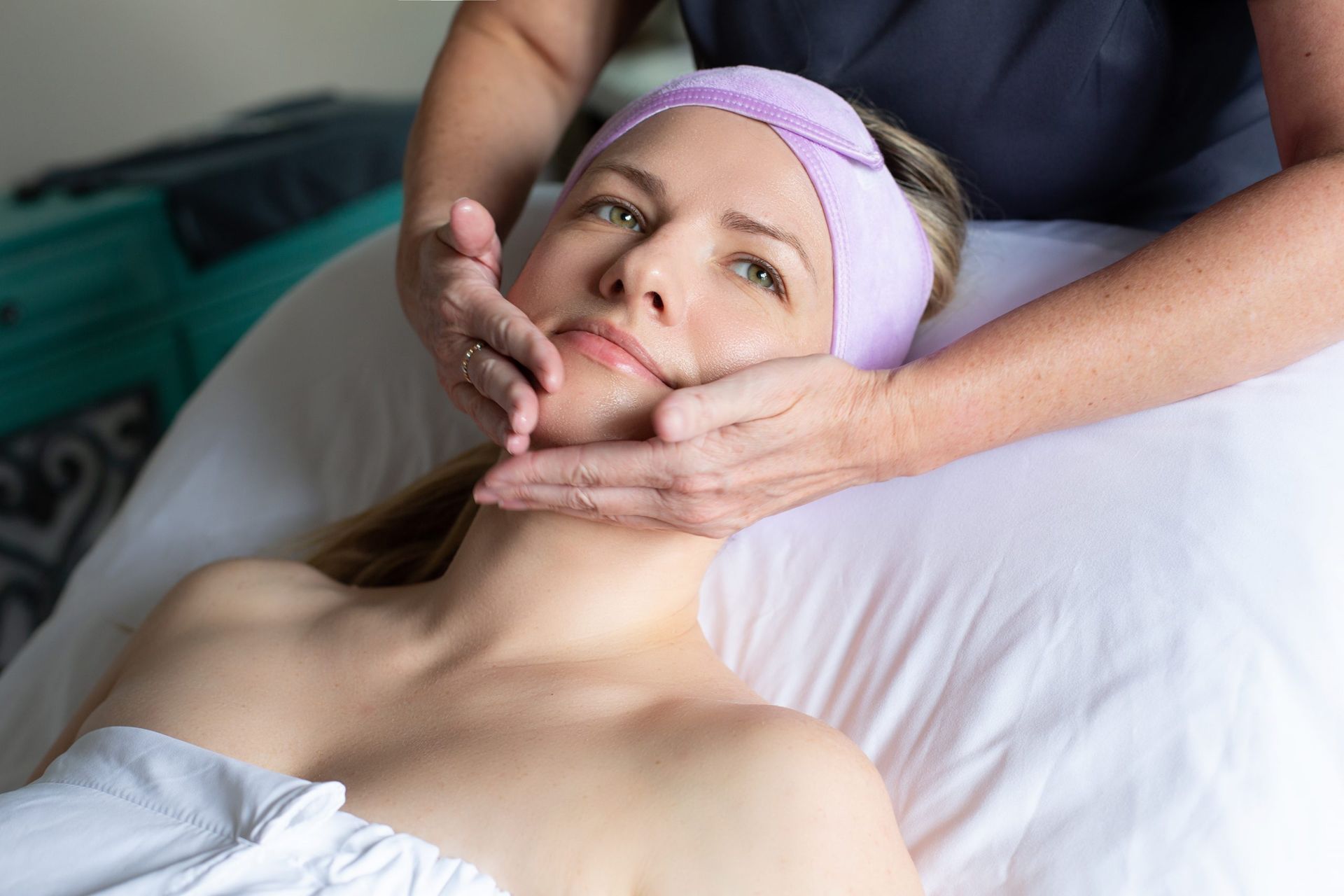 A woman is getting a facial massage at a spa.