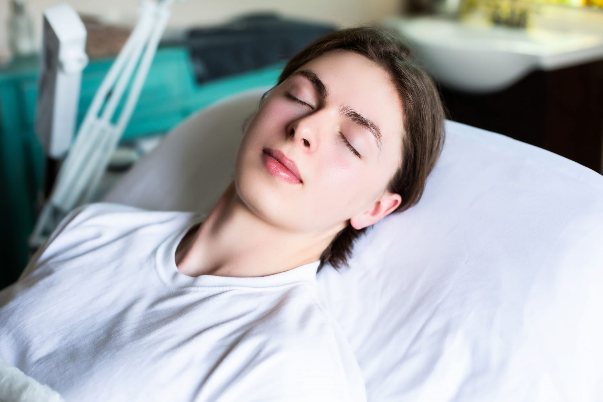 A young man is laying on a bed with his eyes closed.