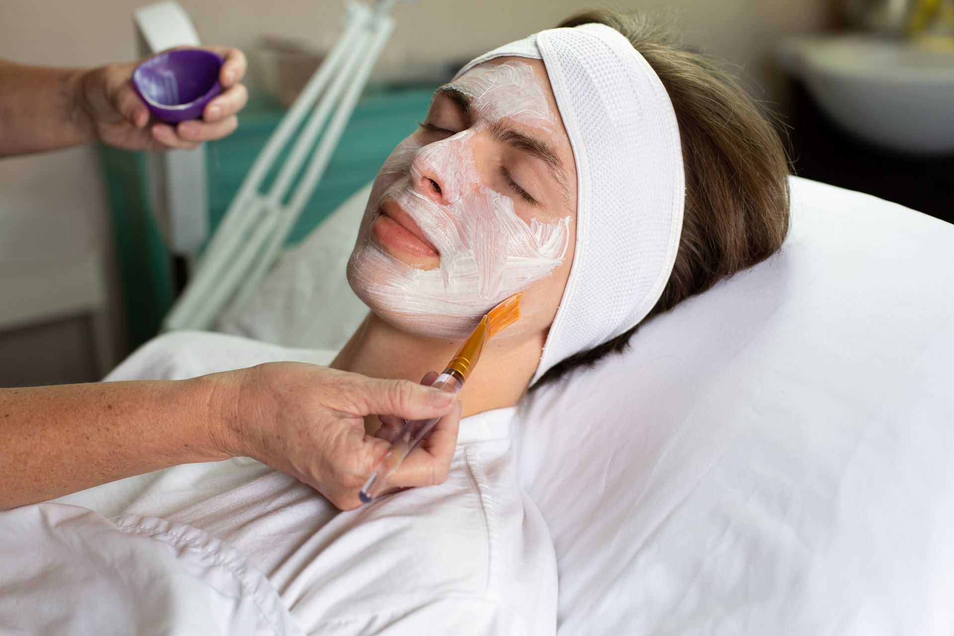 A woman is getting a facial treatment in a spa.